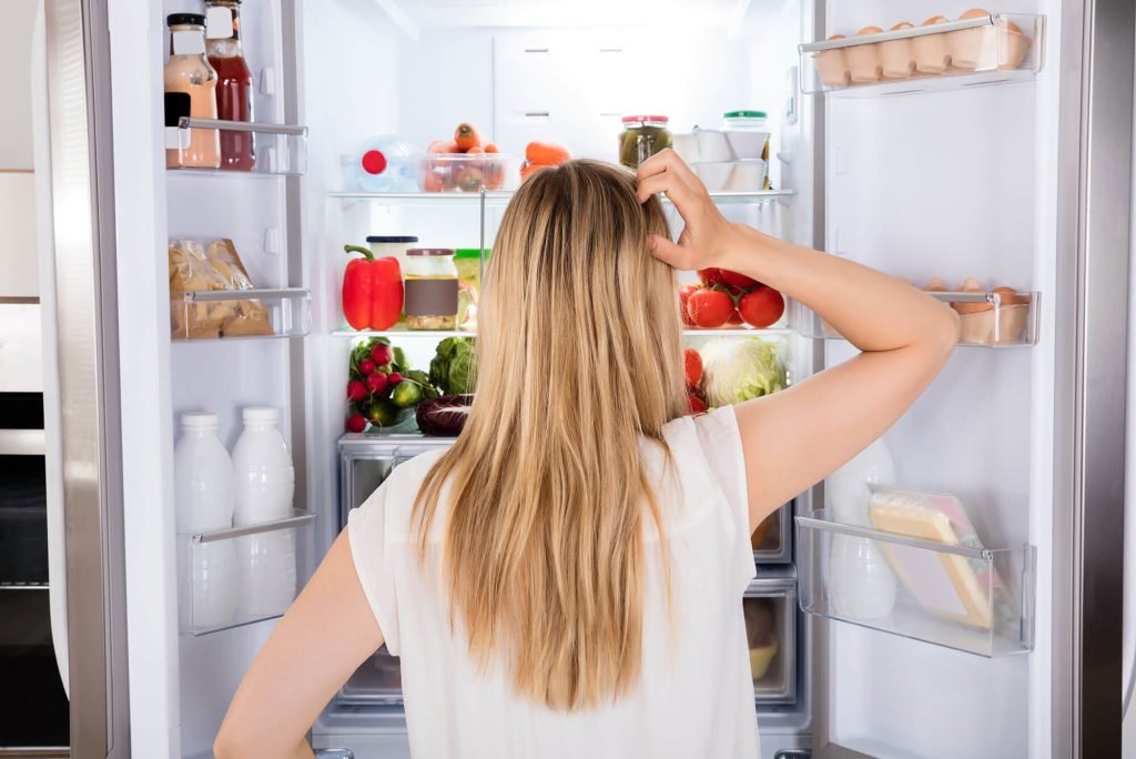 Woman gazing at refrigerator in kitchen setting.